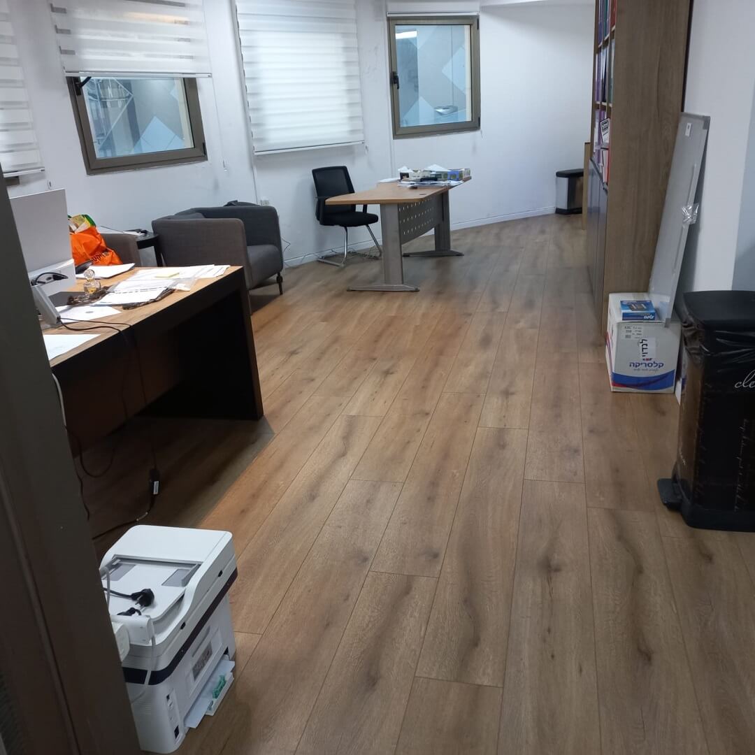 משרד עם רצפת פרקט נקייה ושולחנות עבודה מסודרים